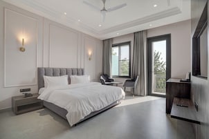 Un dormitorio moderno con una cama grande, un ventilador de techo y vistas al exterior a través de una ventana.