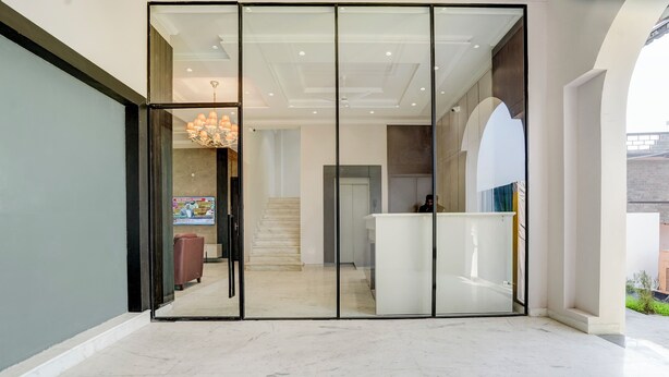 A spacious lobby with a marble floor, a reception desk, and a staircase leading to upper floors. - Nirvana Hotel & Banquet (Batala)