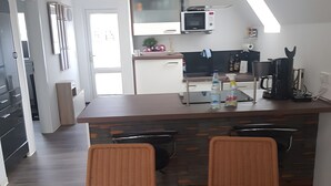 Une cuisine moderne avec un coin repas, comprenant un îlot de cuisine, deux chaises en osier et une table à manger.