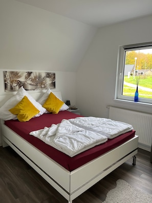 A bedroom with a bed, a window, a radiator, and a wall art piece. - Holiday Home Joschko with Private Terrace and Wi-Fi in Bad Arolsen (Bad Arolsen)