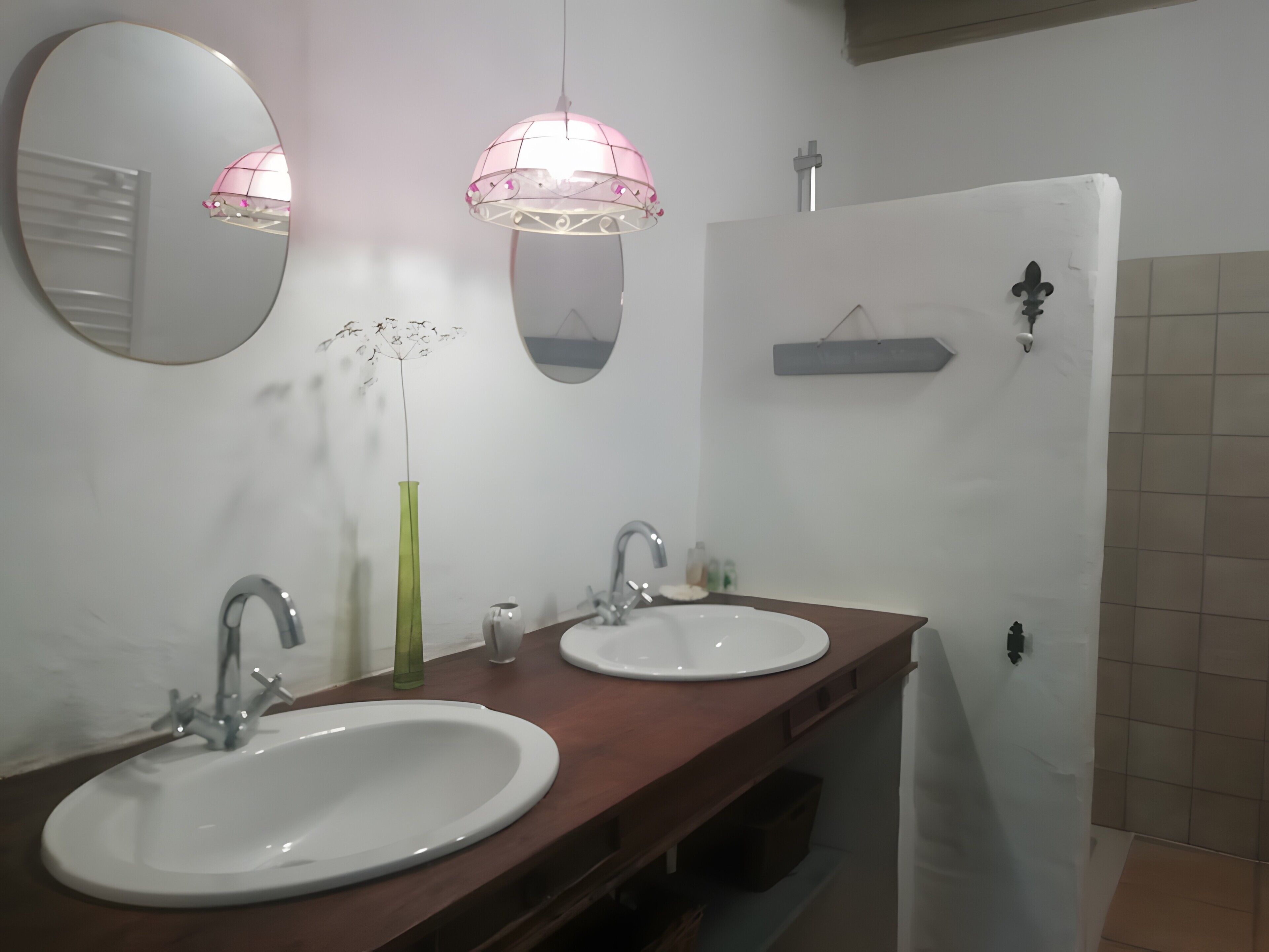 Ein Badezimmer mit zwei Waschbecken, einem Spiegel, einer Pendelleuchte und einem Handtuchhalter.