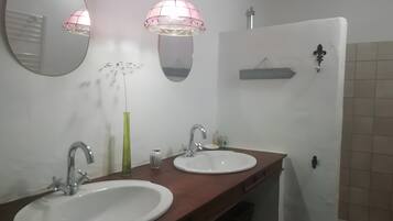 Ein Badezimmer mit zwei Waschbecken, einem Spiegel, einer Pendelleuchte und einem Handtuchhalter.