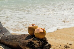Twee kokosdranken op een boomstronk aan het strand.