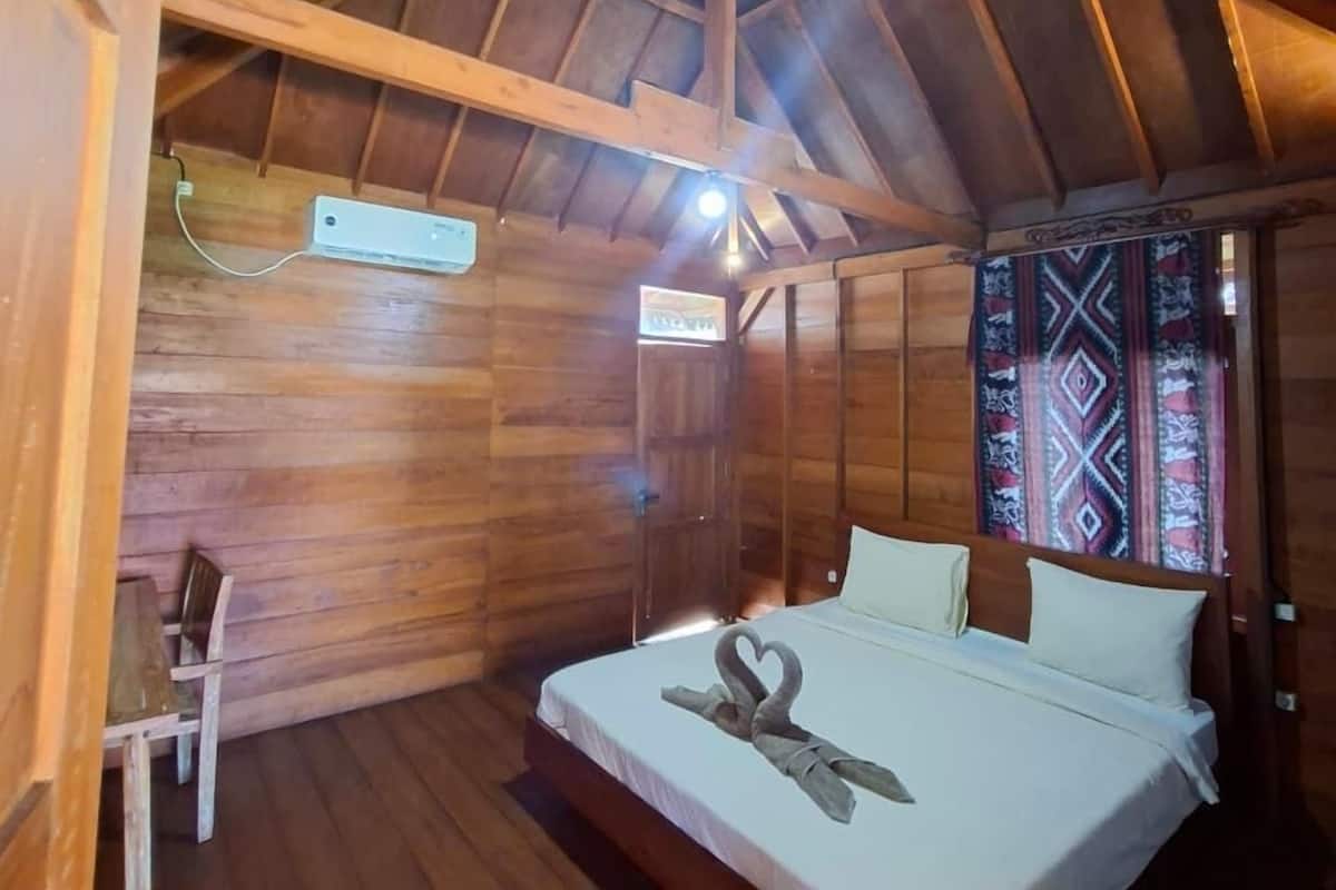 A wooden cabin bedroom with a bed, a chair, and a ceiling light.