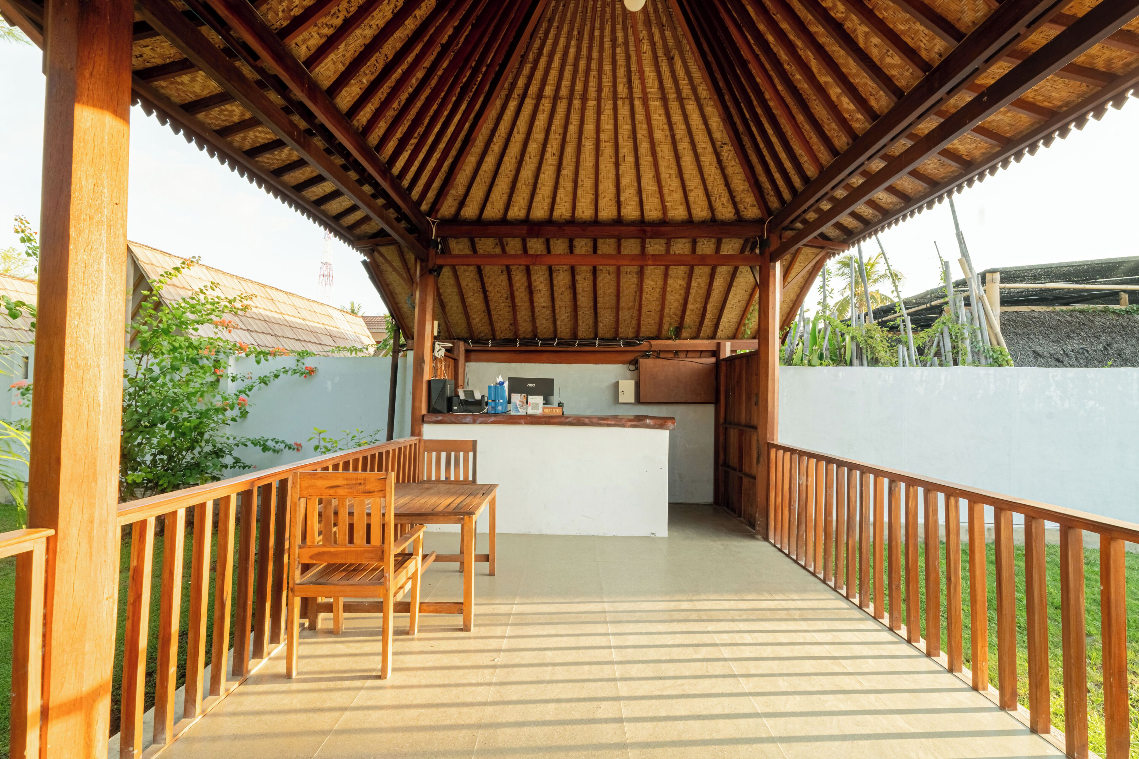 A covered outdoor area with a wooden table and chairs, a small counter, and a view of the surrounding landscape.