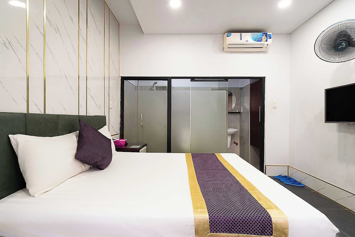 Ein Hotelzimmer mit Bett, Schrank, Spiegel, Fernseher und Klimaanlage.