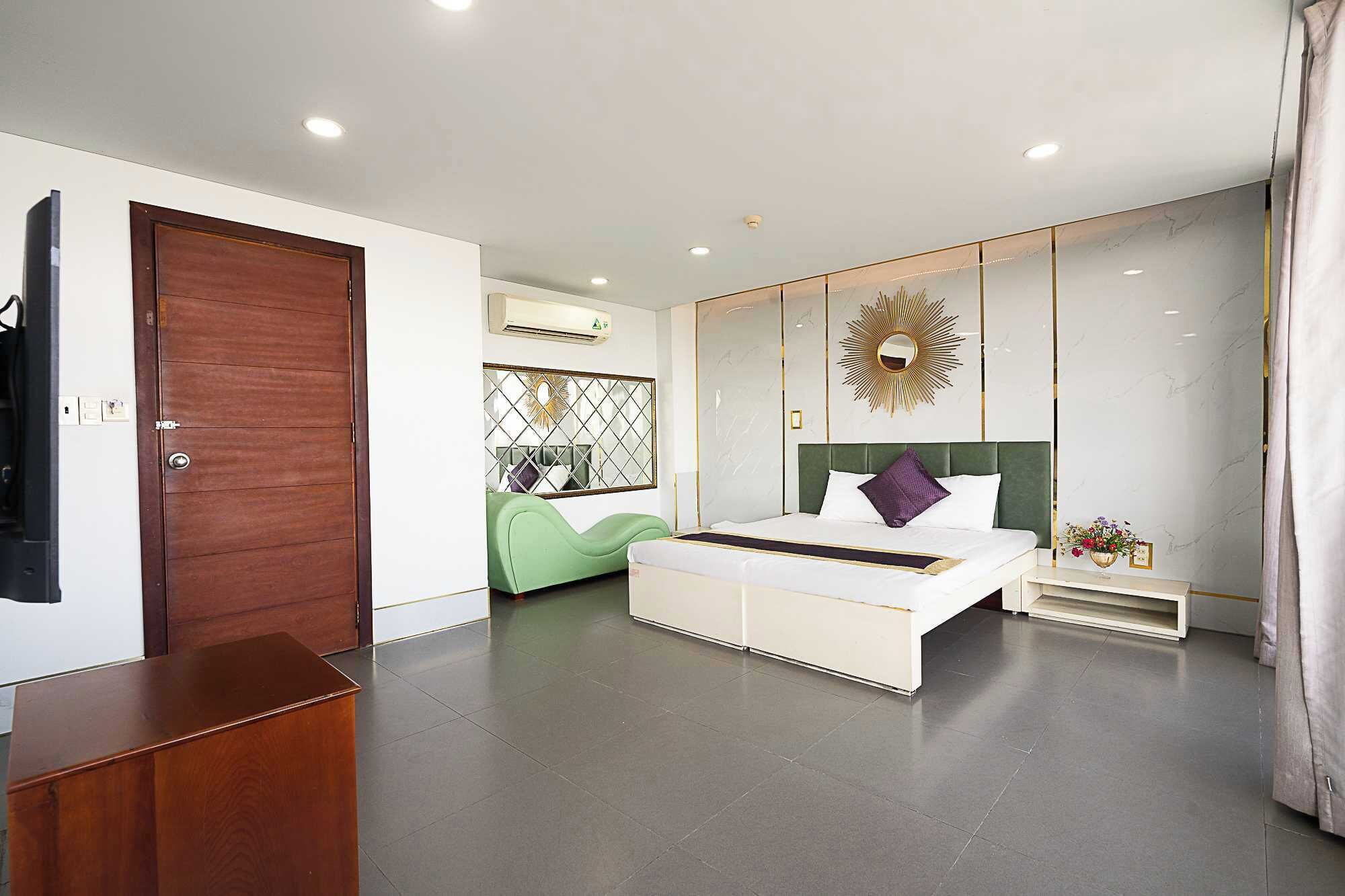 A modern bedroom with a large bed, a green chair, and a wooden desk.