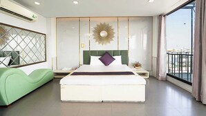 Um quarto moderno com uma cama grande, um sofá verde, um espelho decorativo e vista para o exterior.