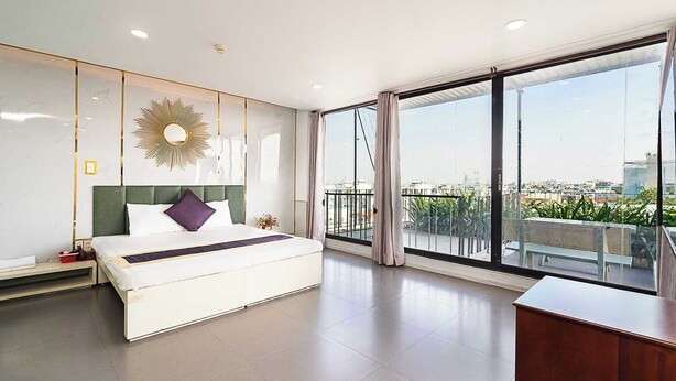 Quarto de hotel moderno com uma cama grande, uma escrivaninha e uma varanda com vista para a cidade.