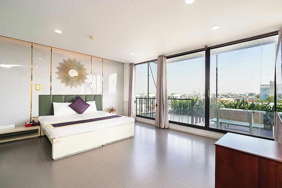 Ein modernes Hotelzimmer mit einem großen Bett, einem Schreibtisch und einem Balkon mit Blick auf die Stadt.