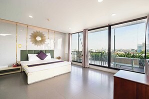 Quarto de hotel moderno com uma cama grande, uma escrivaninha e uma varanda com vista para a cidade.