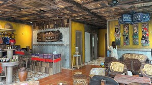 A hotel lobby with wooden ceiling beams, a sign reading "Zao Hotel", and traditional artwork on the walls. - ZAO Hotel Firework & Sea View (Phu Quoc)