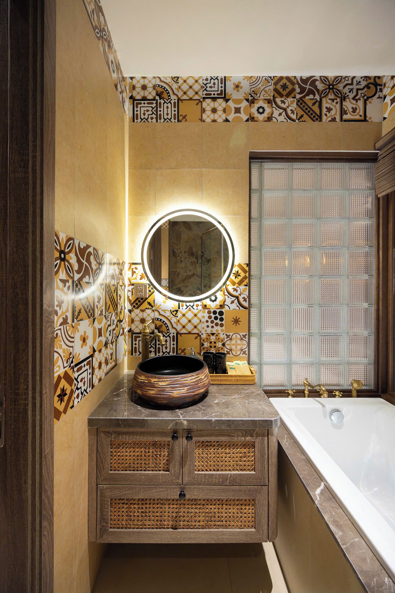 Un bany amb un mirall rodó, una banyera i un lavabo amb un bol decoratiu.