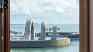 A waterfront architectural structure with three prominent arches, a body of water, and palm trees in the foreground. - ZAO Hotel Firework & Sea View (Phu Quoc)