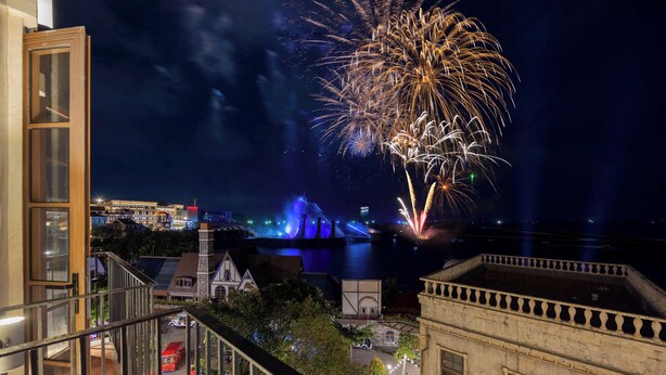 A night view from a balcony overlooking a waterfront with buildings and a bridge. - ZAO Hotel Firework & Sea View (Phu Quoc)