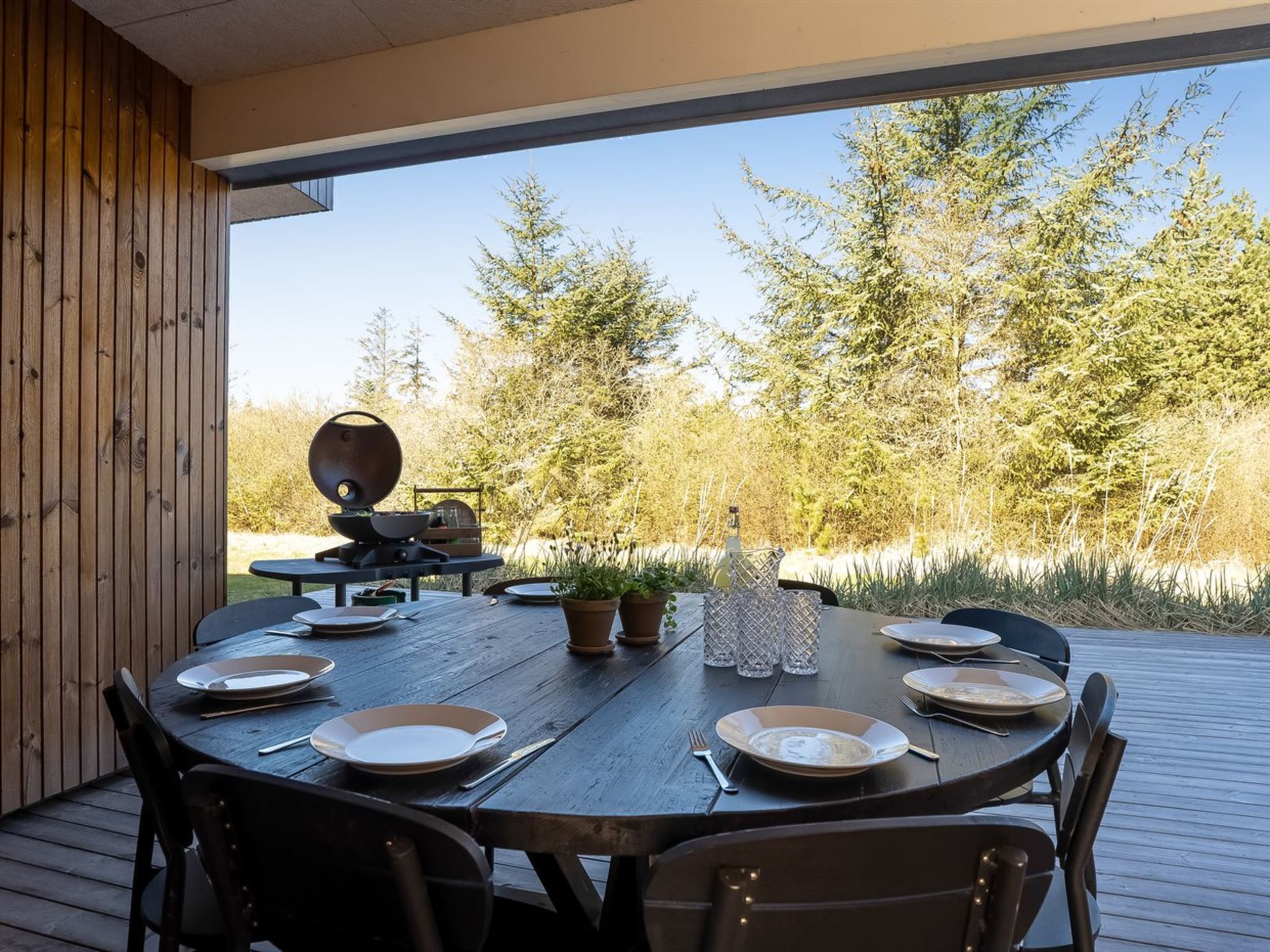 An outdoor dining area with a round table, chairs, and a grill.