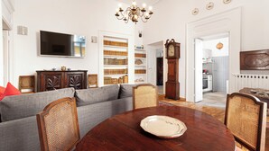 A living room with a dining table, sofa, and bookshelf. - Teresella Suite (Naples)
