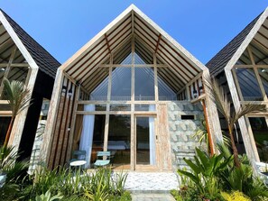Une maison moderne avec un toit triangulaire, de grandes fenêtres et une façade en pierre.