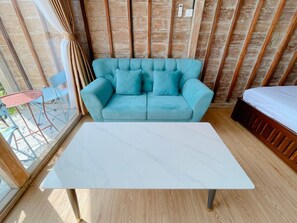 Um quarto com um sofá azul claro, uma mesa branca e piso de madeira.