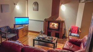 A cozy living room with a television, a fireplace, leather sofas, and a coffee table. - Casa Berrobiaenea  (Lana)
