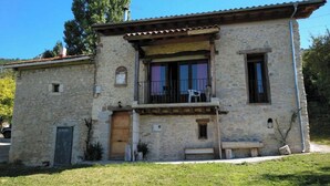 A stone building with a balcony, a wooden door, and a small porch area. - Casa Berrobiaenea  (Lana)