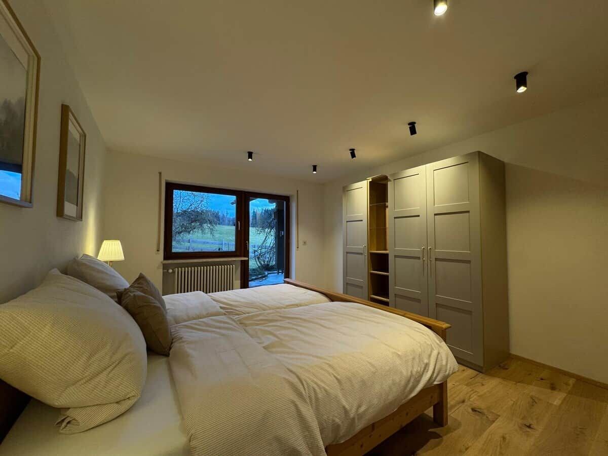 A bedroom with a large bed, a window with a view, built-in wardrobes, and a radiator.