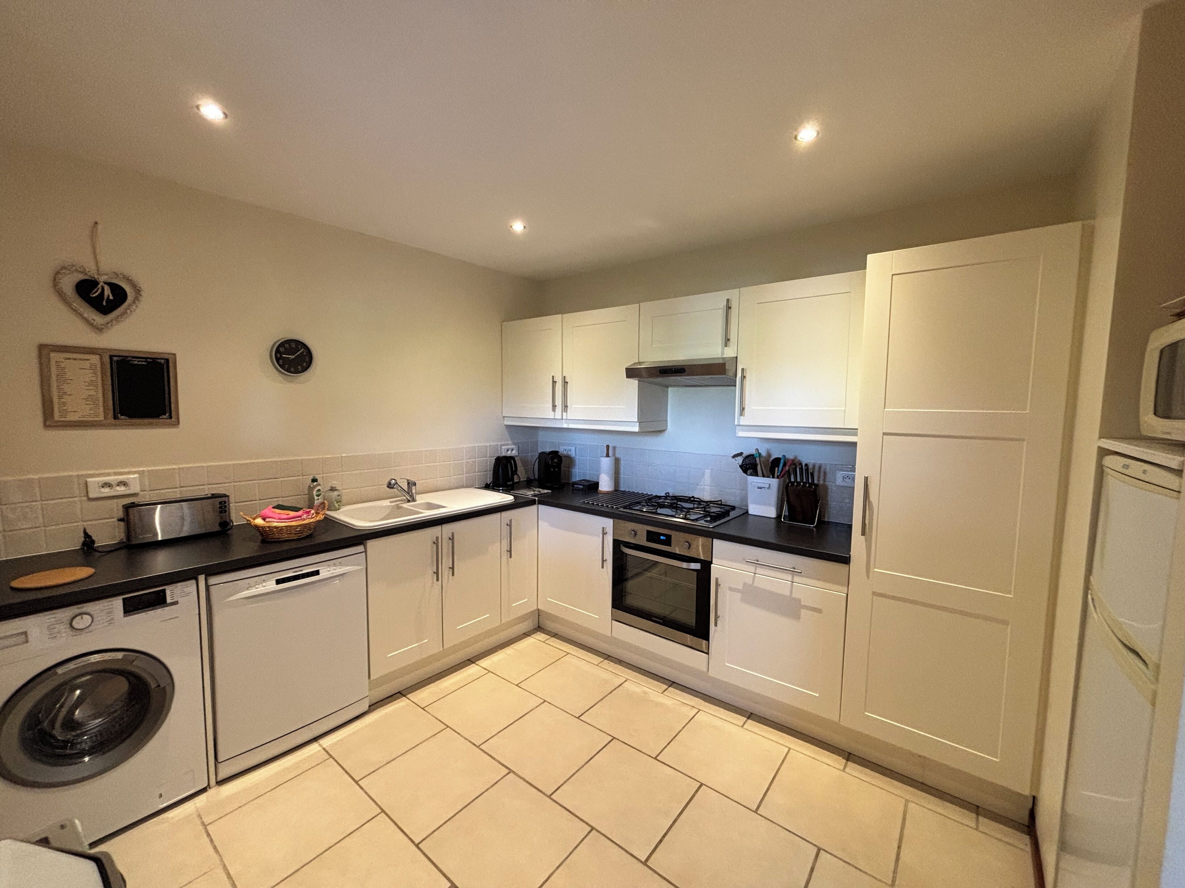 A modern kitchen with white cabinets, a built-in oven, and a dishwasher.