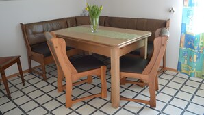A dining area with a wooden table, four chairs, a vase with flowers, and a patterned table runner. - Apartment 'Almer' with Balcony and Wi-Fi (Brilon)