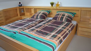 A bed with a patterned bedspread, wooden headboard, and a shelf with decorative items. - Apartment 'Almer' with Balcony and Wi-Fi (Brilon)