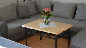 A modern living room with a grey sofa, a small wooden table, and a vase with flowers. - Apartment 'Almer' with Balcony and Wi-Fi (Brilon)