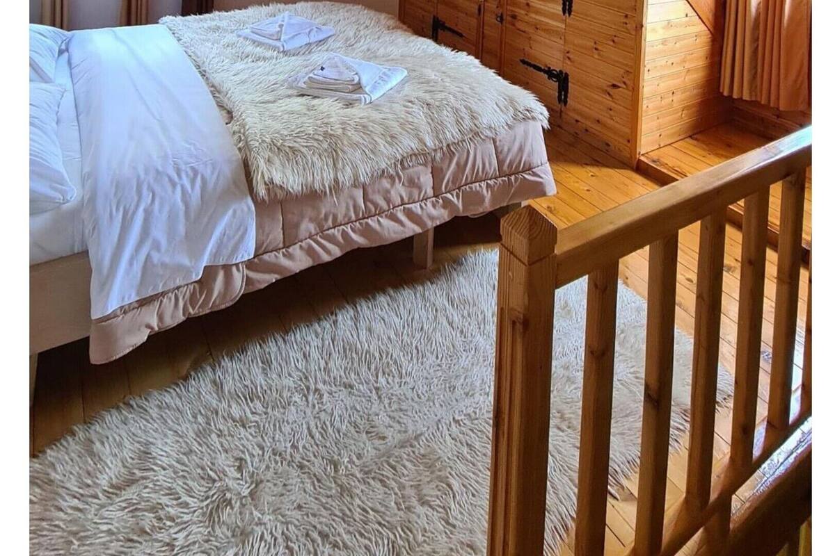 A cozy attic bedroom with a wooden ceiling, a bed, and a small window.