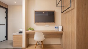 A modern hotel room with a wooden desk, a white chair, a flat-screen TV mounted on the wall, and a small plant on the desk. - Zhishang Hotel Hangzhou West Lake Zheyi  (Hangzhou)