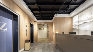 A modern reception area with a wooden floor, a reception desk, and a wall with a mountain landscape mural. - Zhishang Hotel Hangzhou West Lake Zheyi  (Hangzhou)