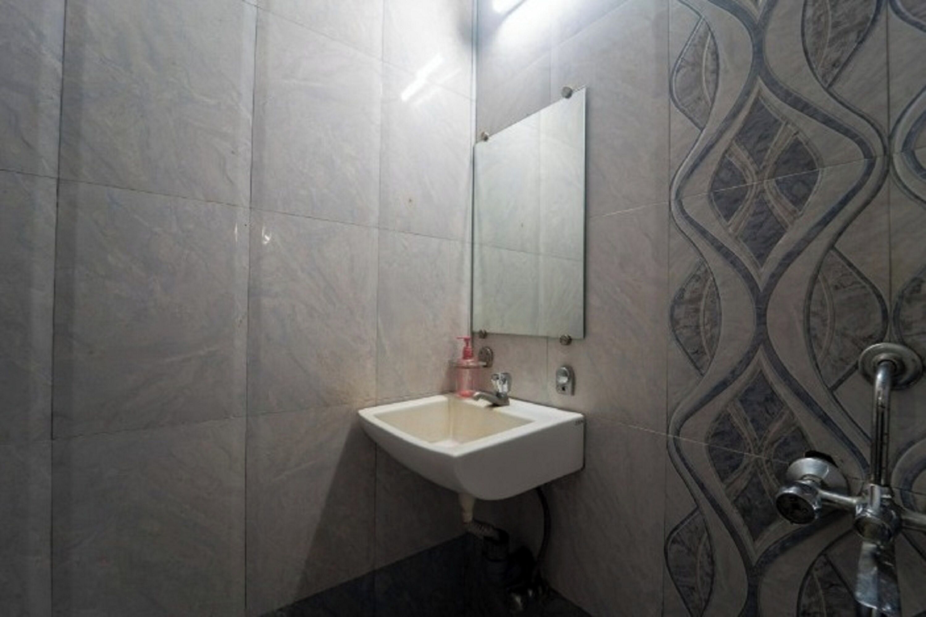 A bathroom with a white sink, a mirror, and a shower with a modern design.