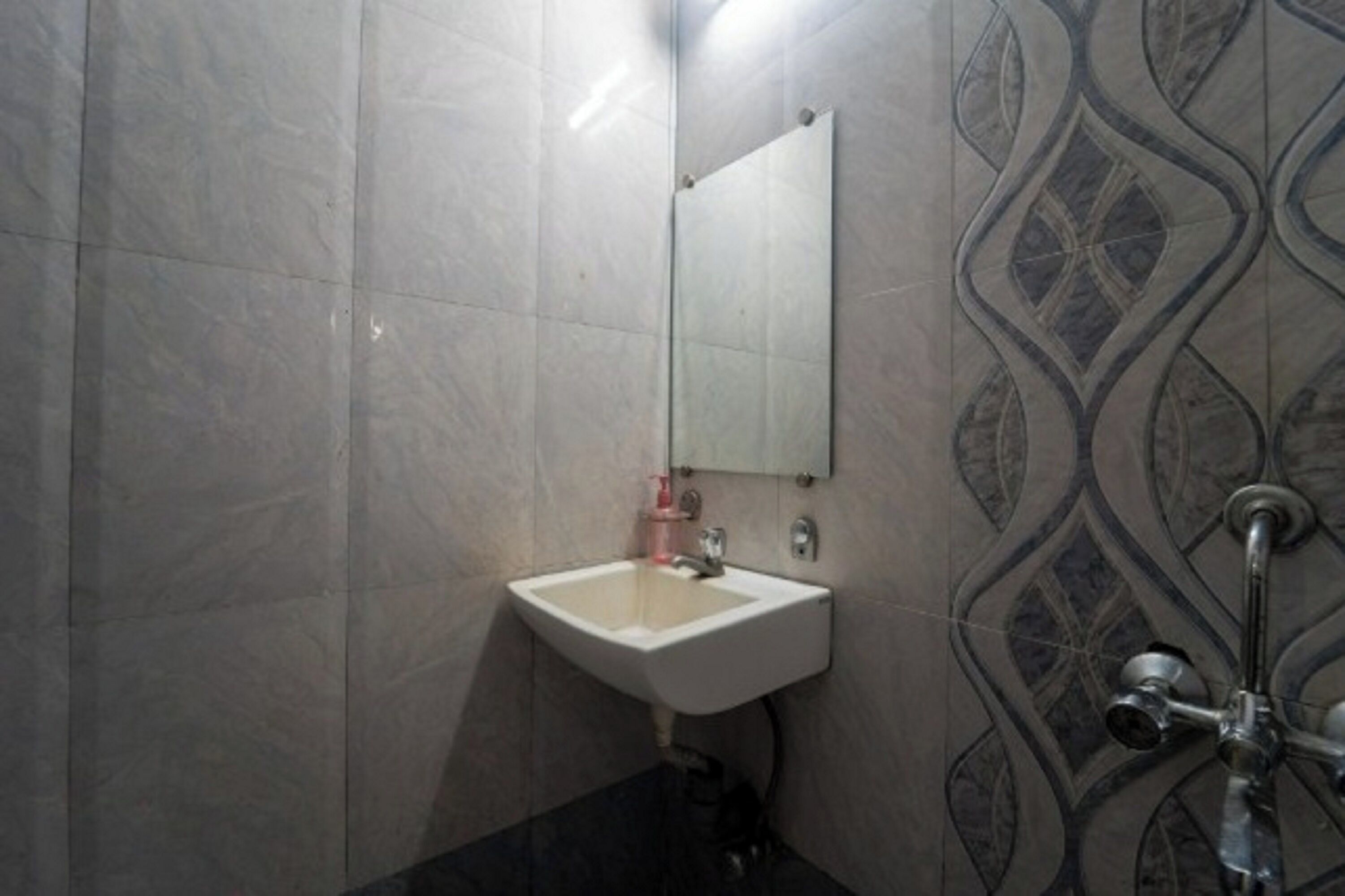 A bathroom with a white sink, a mirror, and a shower with a modern design.