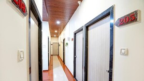 Ein Hotelgang mit Türen mit den Nummern 205 und 208, einer Holzboden und einem roten Teppich.