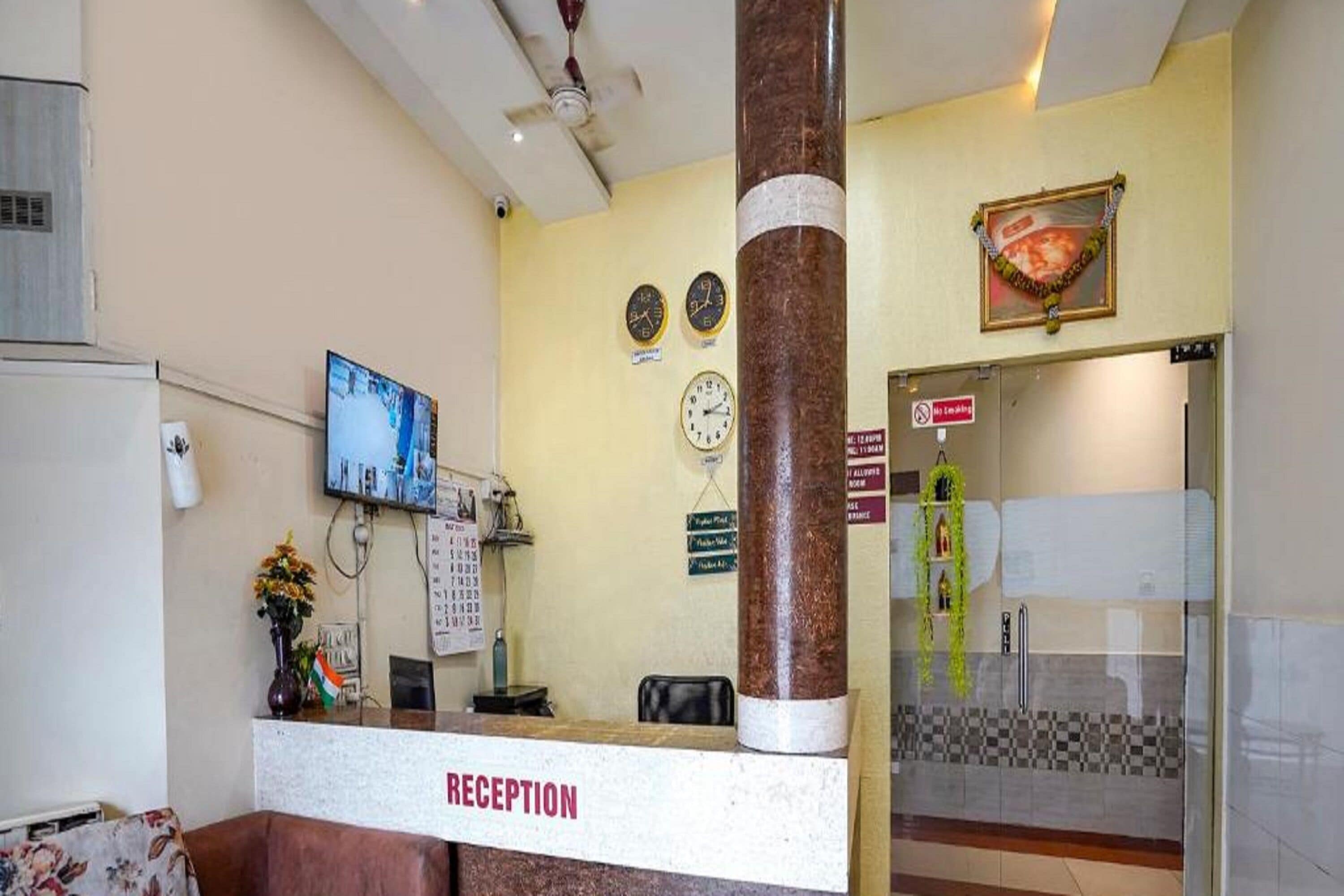 A reception area with a reception desk, a television, clocks, and a pillar.