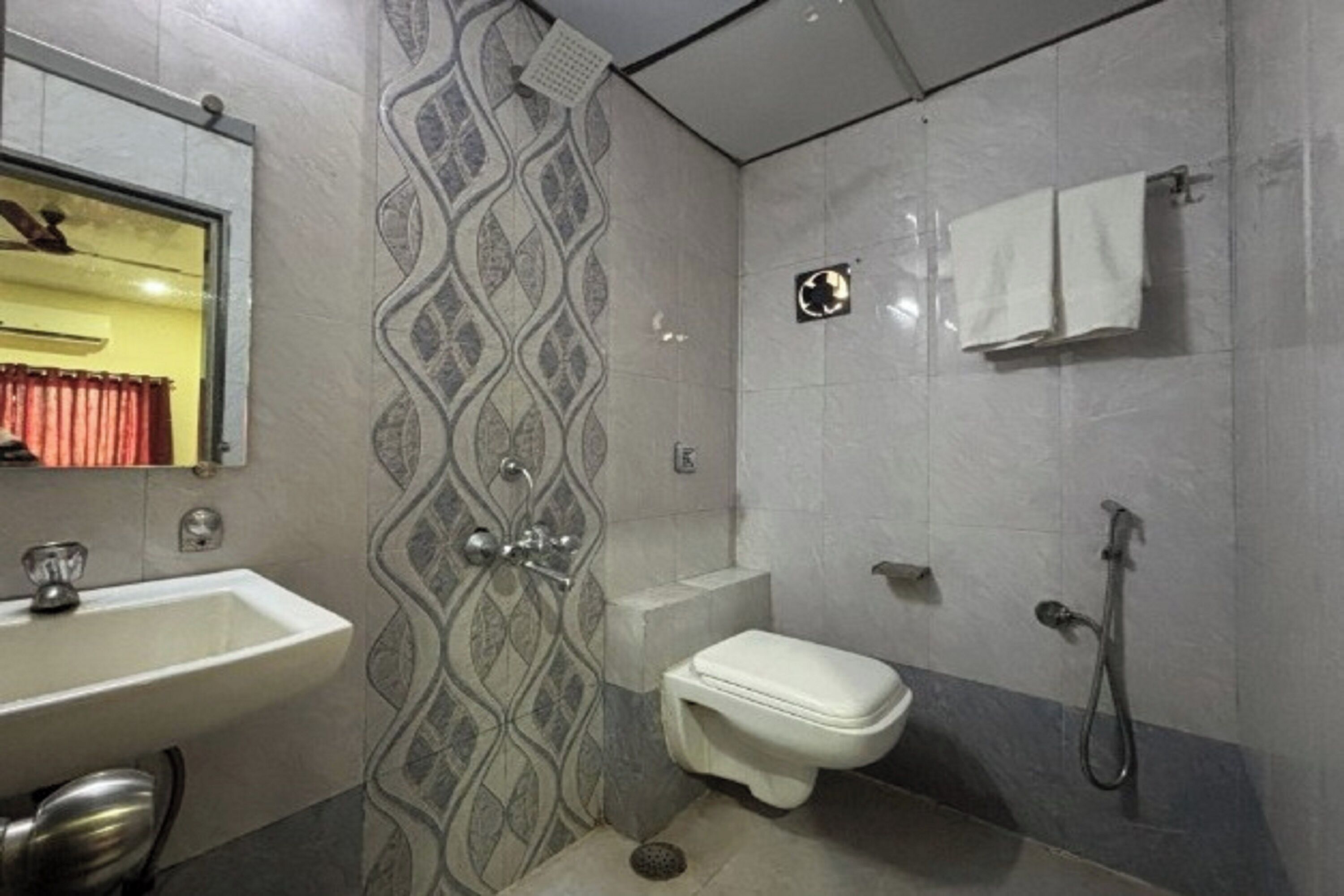 A bathroom with a sink, toilet, shower, and a towel rack.
