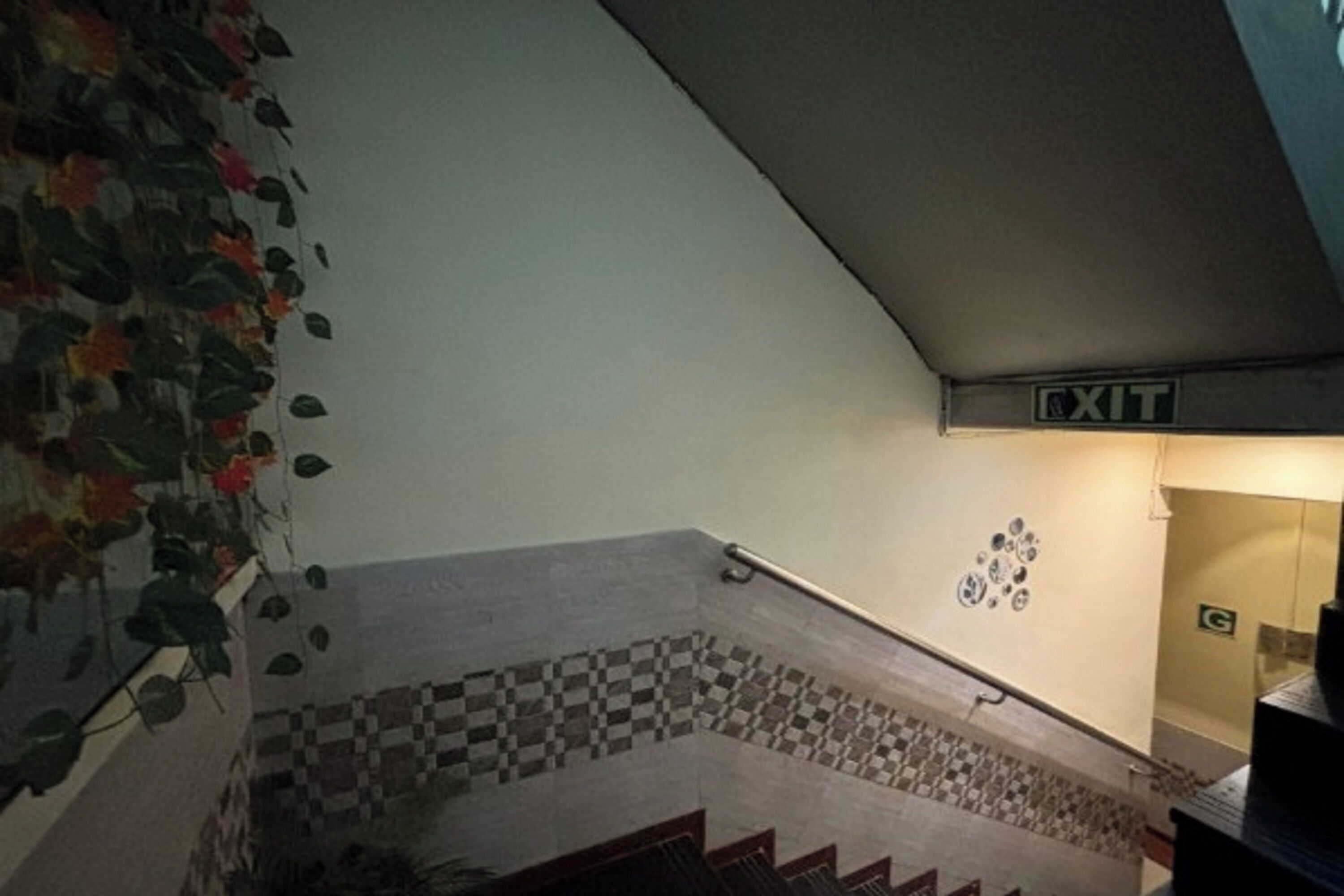 A staircase with a checkered tile pattern, an exit sign, and a wall with a green sign.