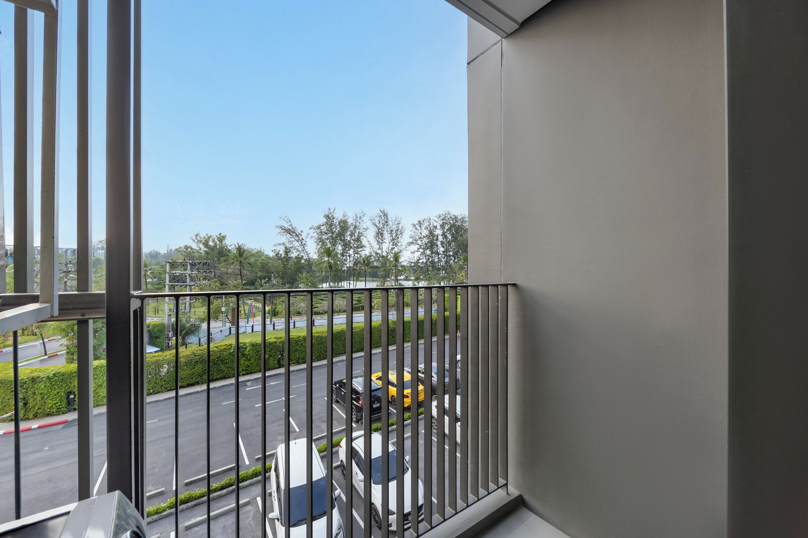 A balcony with a view of a road and greenery.