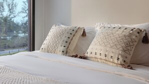 A bed with white bedding and two decorative pillows with a geometric pattern. - Skypark Aurora Laguna Phuket (Choeng Thale)