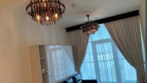Un salon moderne avec un canapé, un téléviseur fixé au mur et deux lustres.