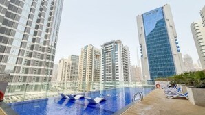 A rooftop swimming pool with lounge chairs, surrounded by high-rise buildings. - 3 Bedroom Apartment at Business Bay - Pool & Spa (Dubai)