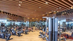 A gym with various exercise equipment, wooden ceiling design, and large windows. - 3 Bedroom Apartment at Business Bay - Pool & Spa (Dubai)