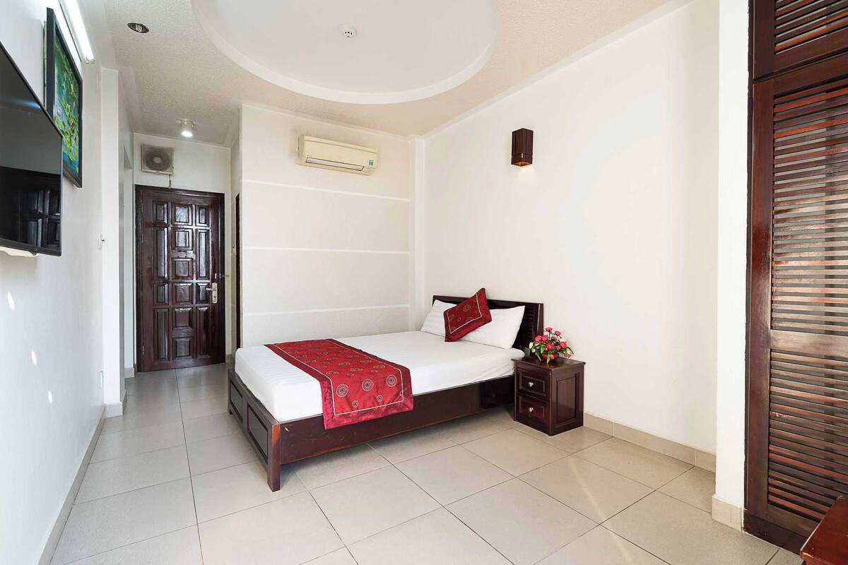 A hotel room with a bed, bedside table, and a TV mounted on the wall.