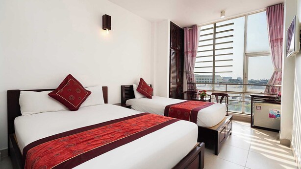 A hotel room with two beds, a balcony with a view, and a large window with curtains. - Collection O Dinh Dinh Hotel - Near Tan Son Nhat Airport (Ho Chi Minh City)