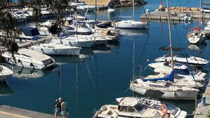 A marina with various boats docked, a clear blue sky, and a distant cityscape. - Modern 2 Bedroom Apartment in Villamartin 3 Pools, Padel, Jacuzzi Sandy Beaches (Villamartín)