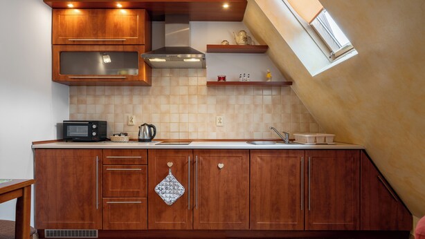 A kitchen with wooden cabinets, a microwave, and a window above the sink. - RentPlanet - Za Cieszynianką (Zakopane)