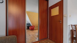 A room with a wooden door, a red chair, and a wooden chair. - RentPlanet - Za Cieszynianką (Zakopane)