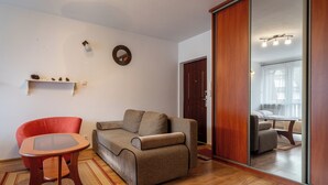 A living room with a sofa, a red chair, a glass-top table, and a wooden floor. - RentPlanet - Za Cieszynianką (Zakopane)